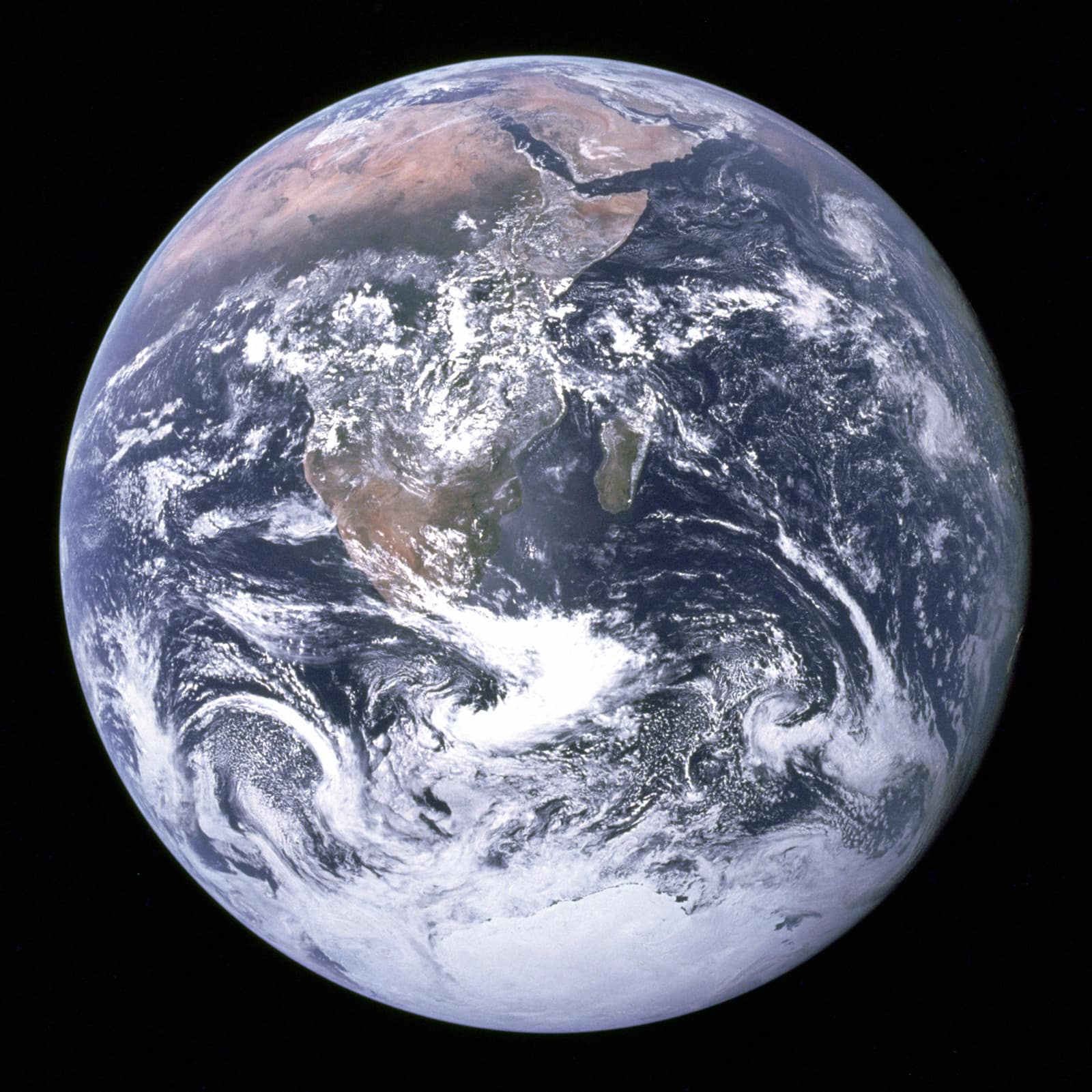 La Terre entière vue de l'espace sur fond noir : une sphère bleue parcourue de nuages blancs, l'Afrique et la péninsule Arabique en brun et ocre près du centre, et la glace blanche de l'Antarctique en bas. Image d'illustration : KEO lui-même n'y figure pas.